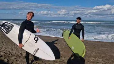 Denizde sörf yapan iki kişinin fotoğrafı