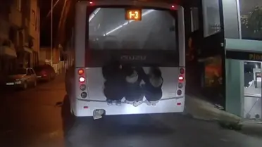 Halk otobüsünün arkasına tutunan üç çocuk